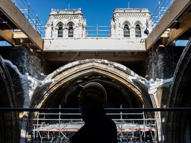 A worker stands on scaffolding under the vault of the Notre-Dame de Paris Cathedral ahead