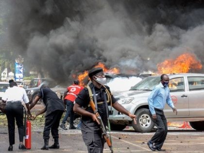 People extinguish fire on cars caused by a bomb explosion near Parliament building in Kampala, Uganda, on November 16, 2021. (Ivan Kabuye/AFP via Getty Images)