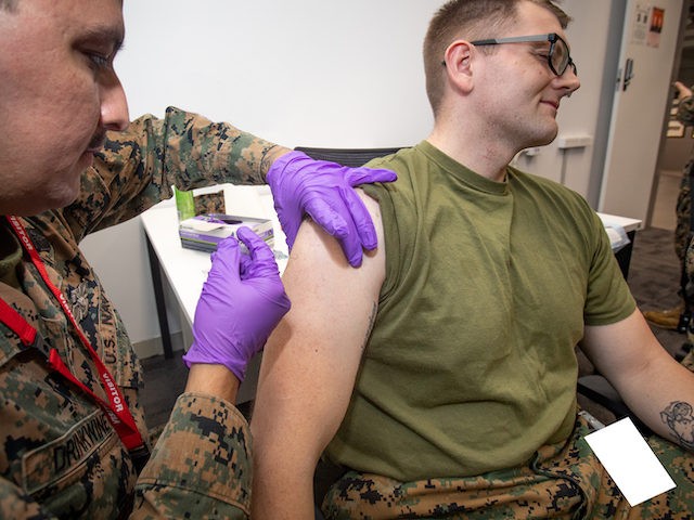 U.S. Marine Corps Sgt. Samuel Davis, right, an intelligence noncommissioned officer in charge with Marine Rotational Force - Darwin, receives an influenza vaccination from U.S. Navy Hospitalman Alexander Drinkwine, a field medical technician with MRF-D, at Larrakeyah Barracks, Darwin, NT, Australia, July 12, 2021. COVID-19 and influenza vaccines were transported …