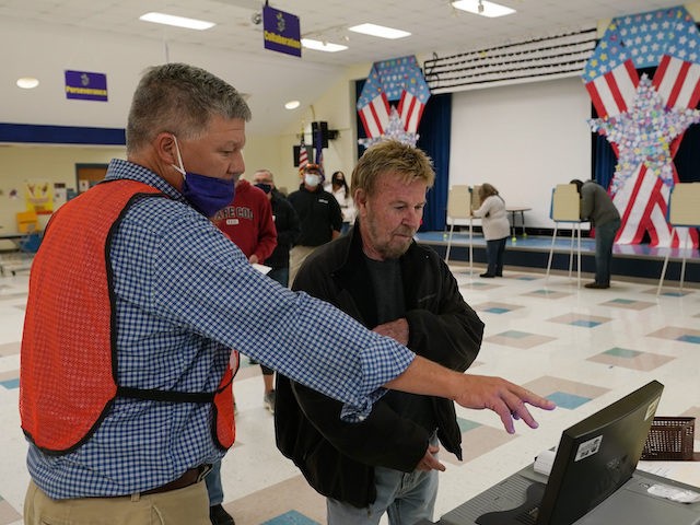 A poll worker, left, helps a voter vote at a school in Midlothian, Virginia, November 2, 2021. (AP Photo/Steve Helber)