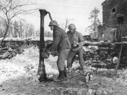 Two American infantrymen fill bottles and a tin hat at a water pump near Samree, in January, 1945, during the Battle of the Bulge in the Ardennes region of Belgium. (AP Photo)