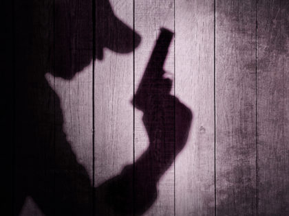 a man with gun in the shadows