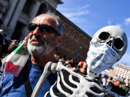 A man holds a reproduction of a human skeleton bearing a protective mask reading "I did not die of Coronavirus but of hunger" as protesters of "No Mask" movements, Covid deniers movements, anti-5G movements and anti-vaccination movements demonstrate against the government's health policy, on October 10, 2020 in front of …