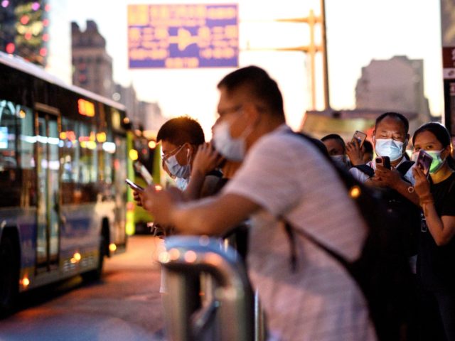 People queue at a bus stop during evening rush hour in Beijing on August 27, 2021. (Photo