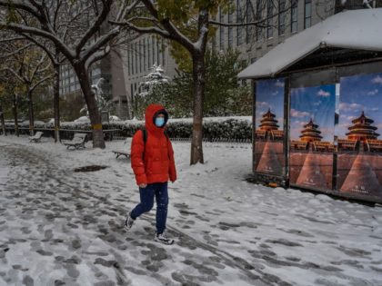BEIJING, CHINA - NOVEMBER 07: A man walks by a closed magazine stand following a snowfall on November 7, 2021 in Beijing, China. Beijing, which averages less than seven days of snow annually, is set to host the Beijing 2022 Winter Olympics next February. (Photo by Kevin Frayer/Getty Images)