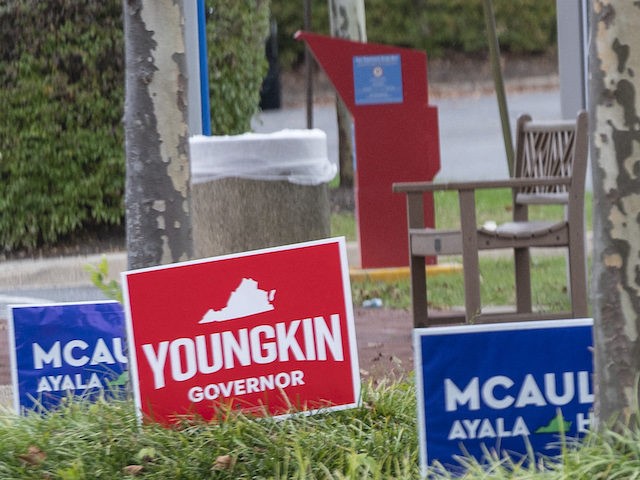 A voter walks past election signs as she walks to the Fairfax County Government Center pol