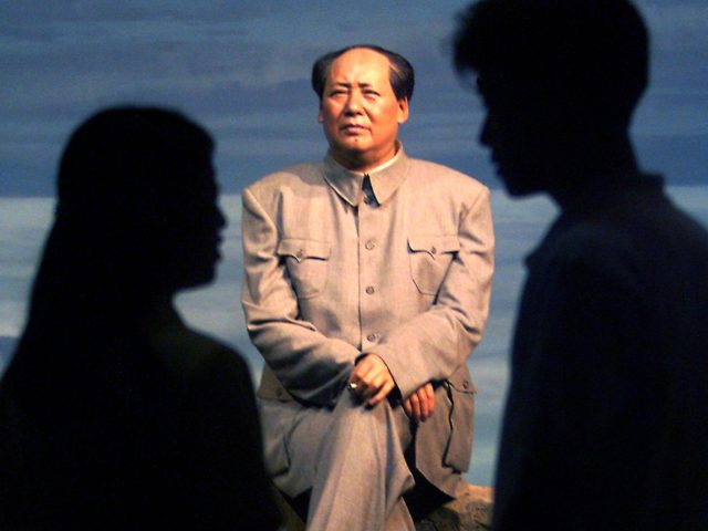 Young Beijingers talk while viewing a wax model of China's late chairman Mao Zedong, sitting on a tree stump in the mountains, on display at the Museum of Chinese Revolution 25 June 1999. Though millions of people died during Mao's rule from starvation during the Great Leap Forward and persecution …