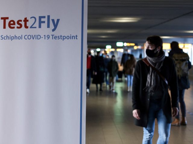 A passenger walks past a sign displaying the way to a Covid-19 test centre at the Schiphol airport on November 29, 2021. - Dutch health authorities said November 29 they have found another case of the new Omicron Covid-19 variant among passengers arriving from South Africa, bringing the total to …
