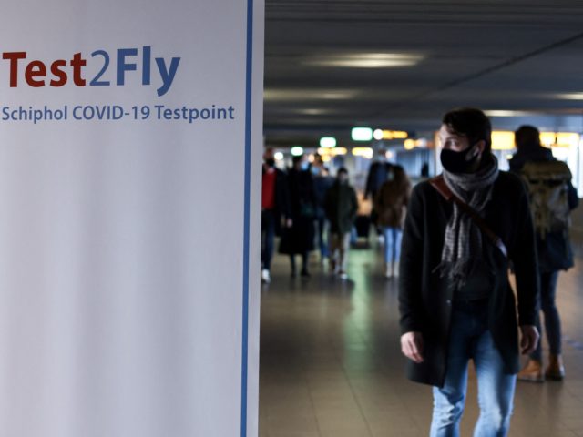 A passenger walks past a sign displaying the way to a Covid-19 test centre at the Schiphol