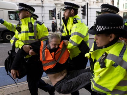 LONDON, ENGLAND - OCTOBER 25: Police officers remove an 'Insulate Britain' protester who was part of a demonstration blocking Upper Thames Street, near Southwark Bridge on October 25, 2021 in London, England. The protest group, which calls for the government to insulate all homes in the UK by 2030 to …