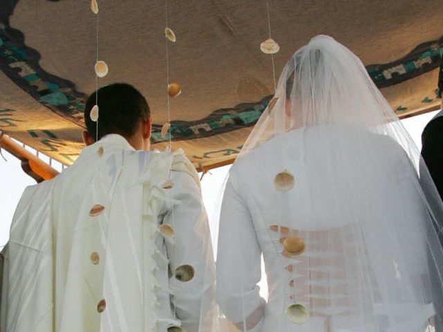 NEVE DEKALIM, -: Israeli settler bride and groom, Joseph Hanun, 22, and Hadas Neuman, 20, stand under a 'chupa', a Jewish altar, during their wedding ceremony in the southern Gaza Strip Gush Katif settlement of Neve Dekalim, 22 June 2005. Israel is to withdraw all soldiers and more than 8,000 …