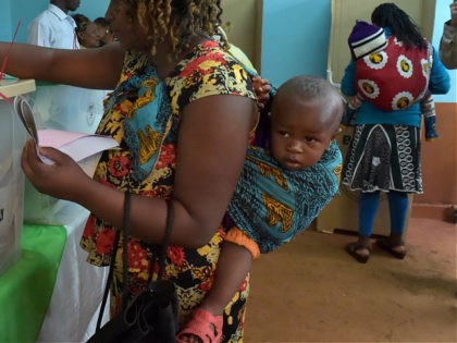 A woman carrying a baby on her back casts her ballot at a polling station in Gatundu South, Kiambu county, during general elections on August 8, 2017. Kenyans were voting on August 8 in elections headlined by a knife-edge battle between incumbent Uhuru Kenyatta and his rival Raila Odinga that …
