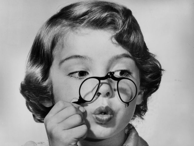 circa 1945: Promotional headshot portrait of a young girl puckering her lips and peering through an antique pince-nez. (Photo by Hulton Archive/Getty Images)