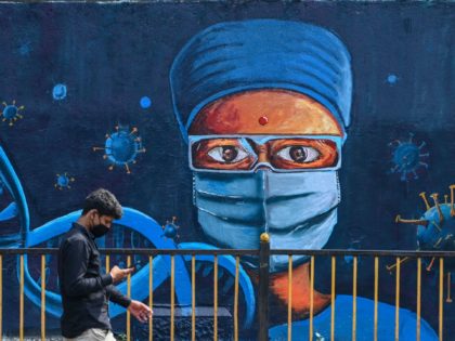 A man walks past a wall mural depicting a health worker to spread awareness about the Covi