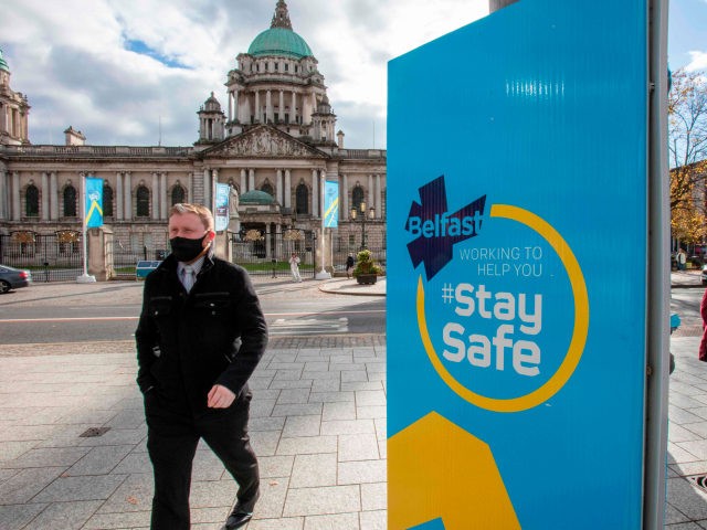 Pedestrians wearing face masks as a precaution against the transmission of the novel coronavirus walk by signage with the hashtag 'staysafe' in Belfast on October 16, 2020, as Northern Ireland imposes tighter coronavirus restrictions amid an uptick in cases. - Northern Ireland authorities on October 14 ordered the closure of …
