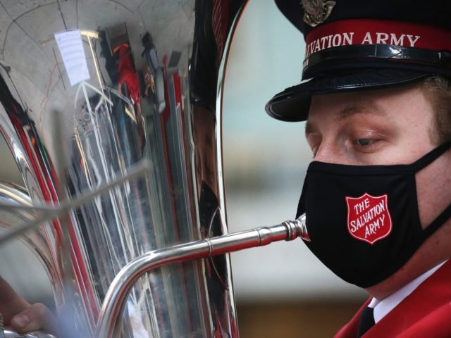 LOS ANGELES, CALIFORNIA - DECEMBER 10: A Salvation Army band member wears a face mask while performing during a drive-thru red kettle donation collection in front of the TCL Chinese Theatre along Hollywood Boulevard on December 10, 2020 in Los Angeles, California. This year the Salvation Army is offering a …