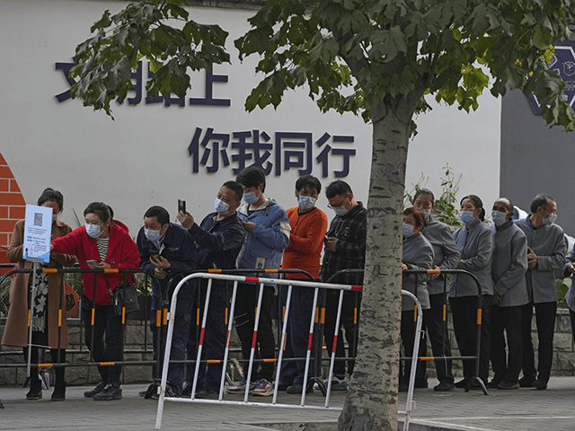 Service sector workers wearing face masks to help curb the spread of the coronavirus line up for COVID-19 test during a mass testing at a site baring the words "You and me on the road of civilization" in Beijing, Friday, Oct. 29, 2021, following a spike of the coronavirus in …