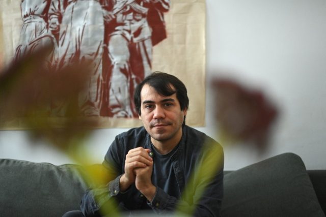 Cuban artist Hamlet Lavastida sits next to one of his works of art after an interview with