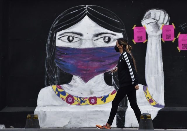 A woman walks in front of graffiti before a demonstration to mark the International Day fo