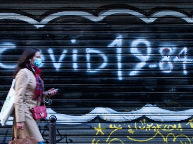 A woman wearing a face mask walks past the closed iron curtain of a restaurant on which is written "Covid 19-84" referring to the book by Orwell 1984 on December 10, 2020 in Paris, as France is on a second lockdown in a bid to contain the spread of Covid-19 …