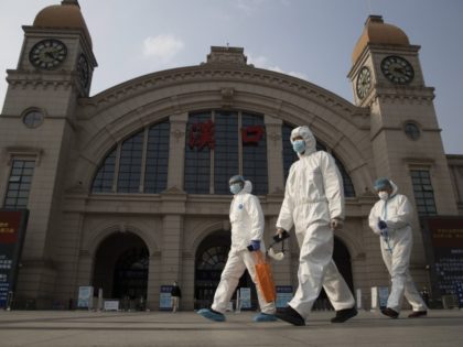 FILE - April 7, 2020, file photo: Workers in protective overalls walk past the Hankou railway station on the eve of its resuming outbound traffic in Wuhan in central China's Hubei province. One year after Wuhan’s lockdown to curb the coronavirus, the Chinese city has long since sprung back to …