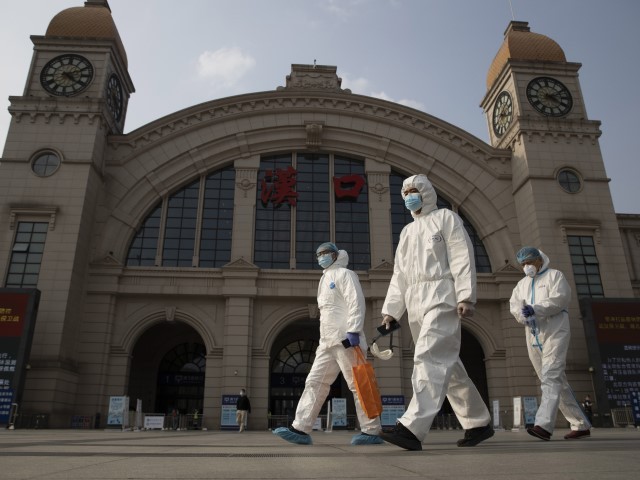 FILE - April 7, 2020, file photo: Workers in protective overalls walk past the Hankou railway station on the eve of its resuming outbound traffic in Wuhan in central China's Hubei province. One year after Wuhan’s lockdown to curb the coronavirus, the Chinese city has long since sprung back to life.