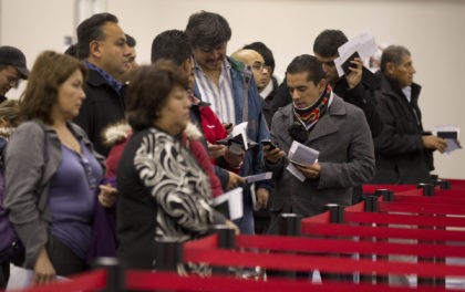 Non-resident visitors to the United States wait in line at immigration control after arriv