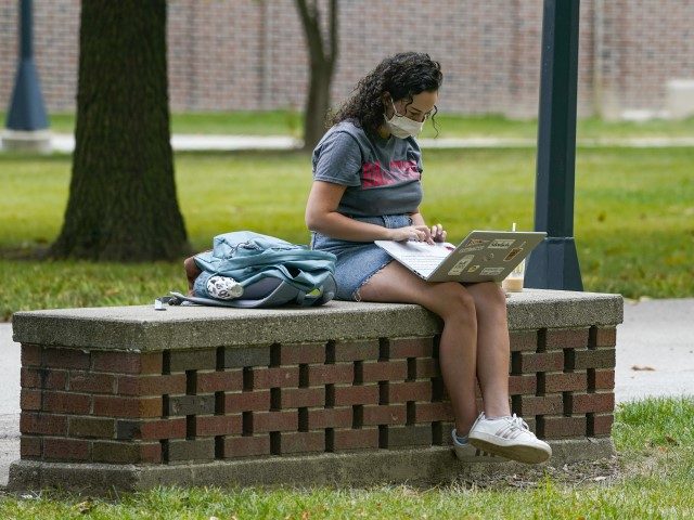 A masked student works on her laptop on the campus of Ball State University in Muncie, Ind., Thursday, Sept. 10, 2020. College towns across the U.S. have emerged as coronavirus hot spots in recent weeks as schools struggle to contain the virus. Out of nearly 600 students tested for the …