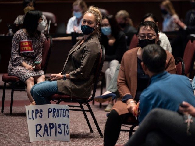 A woman sits with her sign during a Loudoun County Public Schools (LCPS) board meeting in Ashburn, Virginia on October 12, 2021. - Loudoun county school board meetings have become tense recently with parents clashing with board members over transgender issues, the teaching of critical race theory (CRT), and Covid-19 …
