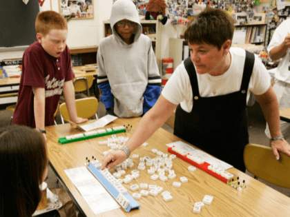 ARLINGTON, VA - JUNE 12: Sixth grade teacher Sandy Tevelin (R) shows students Glenn Kinsman (L) and Gino Rodriguez (C) on how to win as they enjoy a mah-jongg game during their lunch break at Thomas Jefferson Middle School June 12, 2006 in Arlington, Virginia. A group of sixth grade …