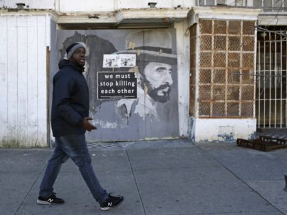In this March 3, 2017 photo, Kelvin Parker, a community outreach worker at U-TURNS, walks past a blighted storefront in west Baltimore. Parker and his colleagues spend part of their shifts walking through a public housing project and past blocks of vacant buildings the same neighborhood where the death of …