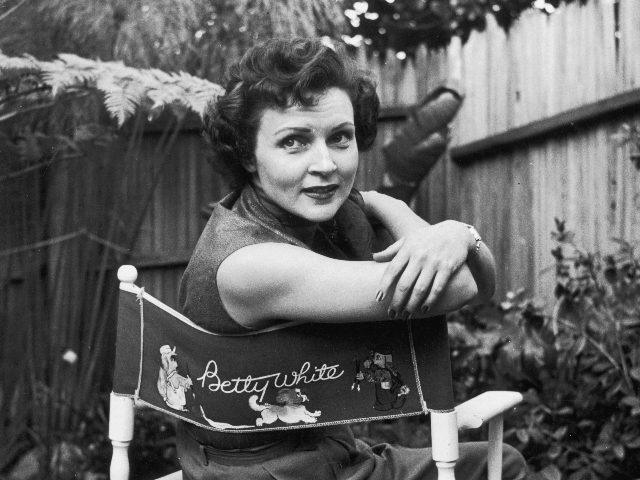 circa 1956: American actor Betty White sits in a canvas chair with her name written on the