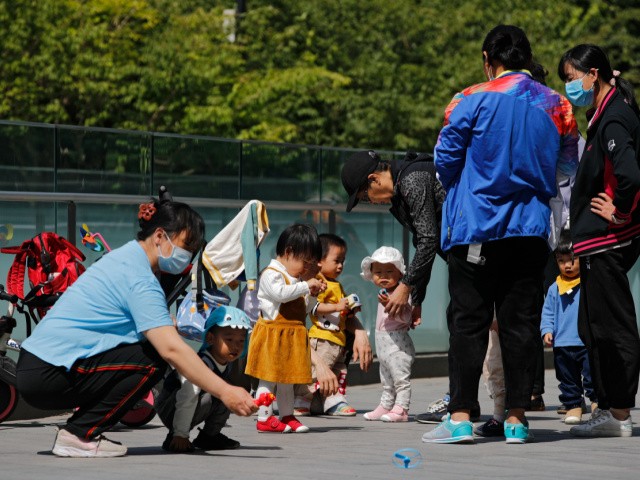 Residents bring their children to play in a compound near a commercial office building in Beijing on May 10, 2021. China's ruling Communist Party will ease birth limits to allow all couples to have three children instead of two to cope with the rapid rise in the average age of its population, a state news agency said Monday, May 31. (AP Photo/Andy Wong)