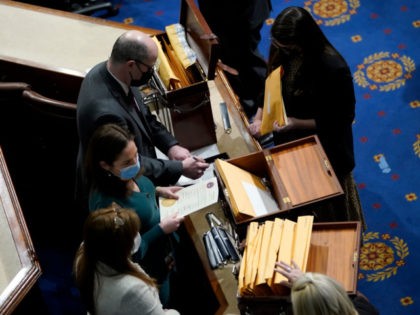 WASHINGTON, DC - JANUARY 06: Congressional aides examine electoral college votes in the House Chamber during a reconvening of a joint session of Congress on January 06, 2021 in Washington, DC. Members of Congress returned to the House Chamber after being evacuated when protesters stormed the Capitol and disrupted a …
