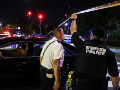 WASHINGTON, DC - JULY 22: A police officer holds up caution tape near the site of a shooting on July 22, 2021 in Washington, DC. Gunfire erupted on a busy street, injuring two and sending others fleeing for safety. A dark sedan was being sought in connection with the shooting …