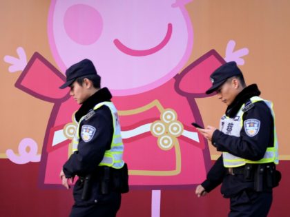 TOPSHOT - This picture taken on January 25, 2019 shows police walking past a Peppa Pig figure on a wall outside the Yu Yuan gardens, a popular tourist spot hosting a 'Peppa Pig pop-up shop' featuring interactive games for children, in Shanghai. - Roasted as a subversive symbol and chopped …