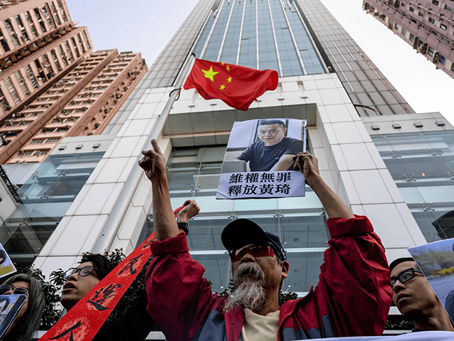A Hong Kong pro-democracy activist (C) holds a placard that translates as "rights activism is not wrong, free Huang Qi" as he attends a protest in support of China's first "cyber-dissident" and founder of human rights website "64 Tianwang" Huang Qi and jailed Chinese human rights lawyer Wang Quanzhang (pictured …