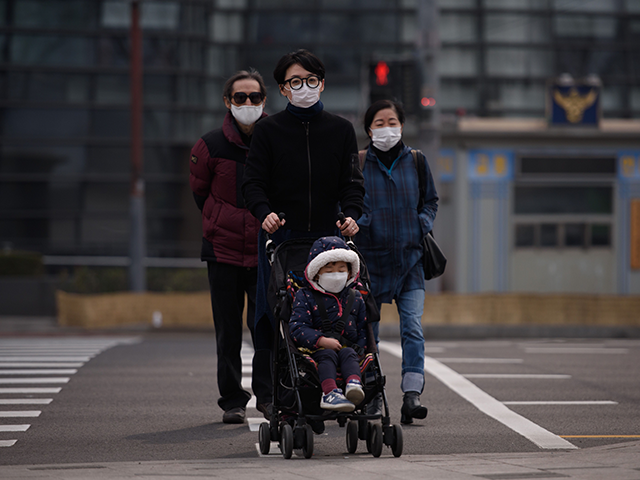 A family wearing face masks cross a road during heavily polluted weather in Seoul on March