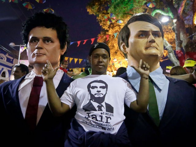 TOPSHOT - A man poses next to giant puppets representing Brazilian President Jair Bolsonaro (R) and Justice Minister Sergio Moro during a traditional carnival parade through the streets of Recife in northeastern Brazil on February 25, 2020. - Puppets of international and local personalities such as leaders Bolsonaro, US Donald Trump, China's Xi Jinping and North Korea's Kim Jong-un along with Swedish activist Greta Thunberg, late US singer Michael Jackson, late British David Bowie and others. (Photo by Leo Malafaia / AFP) (Photo by LEO MALAFAIA/AFP via Getty Images)