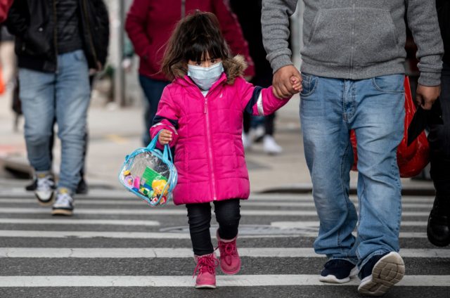 A girl, wearing a mask, walks down a street in the Corona neighborhood of Queens on April 14, 2020 in New York City. - New York will start making tens of thousands of coronavirus test kits a week, its mayor announced Tuesday, as the city looks to boost testing capacity …