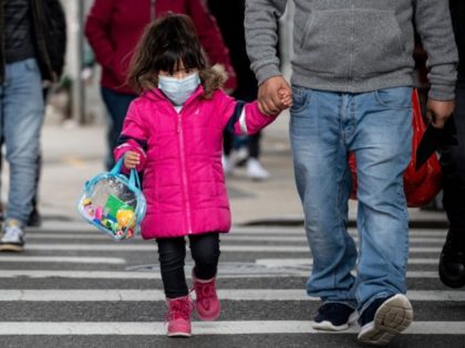 A girl, wearing a mask, walks down a street in the Corona neighborhood of Queens on April 14, 2020 in New York City. - New York will start making tens of thousands of coronavirus test kits a week, its mayor announced Tuesday, as the city looks to boost testing capacity …