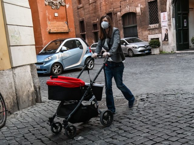 A woman wearing a face mask pushes a baby stroller in central Rome on April 15, 2020, during the country's lockdown aimed at curbing the spread of the COVID-19 pandemic, caused by the novel coronavirus. (Photo by Andreas SOLARO / AFP) (Photo by ANDREAS SOLARO/AFP via Getty Images)