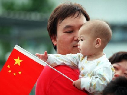 A child plays with the Chinese flag while the parents look on after the Chinese National Day flag raising ceremony 01 October on the Victoria Harbour waterfront. It is the first time the territory has celebrated Chinese National Day under communist Chinese rule.