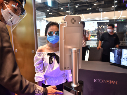 People stand in front of facial recognition software before entering the Icon Siam luxury shopping mall as it reopened after restrictions to halt the spread of the COVID-19 coronavirus were lifted in Bangkok on May 17, 2020. (Photo by Lillian SUWANRUMPHA / AFP) (Photo by LILLIAN SUWANRUMPHA/AFP via Getty Images)