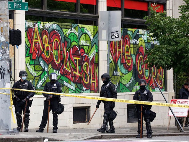 A graffiti that reads "abolish the cops" is pictured as Seattle Police block entrance to t