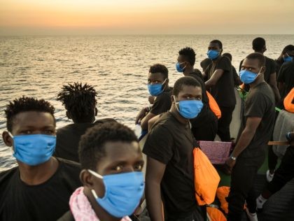 Migrants wearing face masks stand at sunset onboard the Sea-Watch 4 civil sea rescue ship react on sea off the coast of Sicily, Italy, on August 31, 2020. - More than 350 migrants are onboard the Sea-Watch 4, after it took more than 150 people from the German-flagged MV Louise …