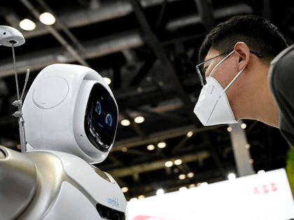 A man wearing face mask looks at a robot at the China National Convention Centre, the venu