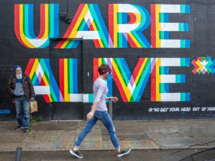 A pedestrian wearing a face mask or covering due to the COVID-19 pandemic, walks past a mural reading "U Are Alive..... so get your head out of your phone" in Dublin on October 19, 2020, amid reports that further lockdown restrictions could be imposed to help mitigate the spread of …
