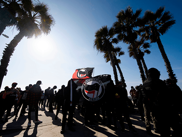 Counter-protesters, some carrying ANTIFA flags, stand beneath palm trees on the beach awaiting to confront demonstrators for a "Patriot March" demonstration in support of US President Donald Trump on January 9, 2021 in the Pacific Beach neighborhood of San Diego, California. (Photo by Patrick T. FALLON / AFP) (Photo by …