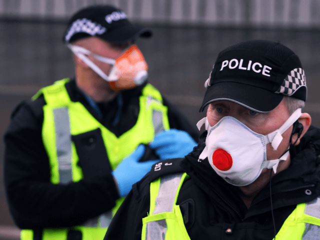 A police officer wwars a PPE face mask outside the Scottish Parliament as members of the public attend an anti lockdown protest held by The Scotland Against Lockdown group in Edinburgh, Scotland on January 11, 2021. (Photo by Andy Buchanan / AFP) (Photo by ANDY BUCHANAN/AFP via Getty Images)